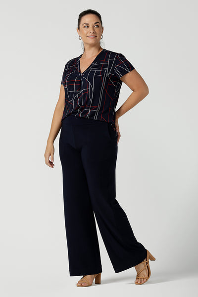 A size 12 women wears a Emily Top in Navy Abstract print. V-neckline with short sleeves on a navy base colour. Geometric print perfect for a corporate office look. Made in Australia for women size 8 - 24.