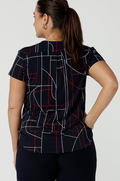 Back view of Size 12 women wears a Emily Top in Navy Abstract print. V-neckline with short sleeves on a navy base colour. Geometric print perfect for a corporate office look. Made in Australia for women size 8 - 24.