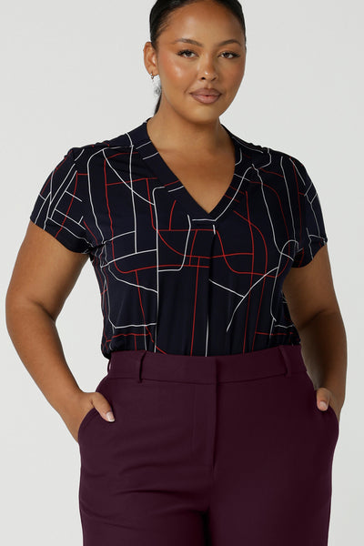 Size 16 curvy woman wears a Emily Top in Navy Abstract print. V-neckline with short sleeves on a navy base colour. Geometric print perfect for a corporate office look. Made in Australia for women size 8 - 24.