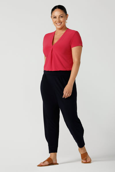 Woman wears fuchsia raspberry Emily top with v-neck and pleat front neckline. Styled back with navy Indi pants in soft jersey. A great work to weekend top with short sleeves. Made in Australia for women size 8 - 24.