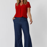 Over 40 year old woman wear red sleeved, v neck top. Australian made from dry touch jersey fabric ensuring a soft, dry feel when wearing -  perfect for the summer heat. This red shirt is an ideal piece for travel as it the dry touch fabric is wrinkle resistant. Shop now in sizes 8-24. Leina & Fleur stock petite and plus sizes. 