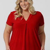 Plus sized woman wears sleeved red top. Australian made from dry touch jersey fabric ensuring a soft, dry feel perfect for the warmer months. This red shirt is an ideal piece for travel as the dry touch fabric is wrinkle resistant. Fashion brand  Leina & Fleur proudly stock petite and plus sizes. Shop now in sizes 8-24.