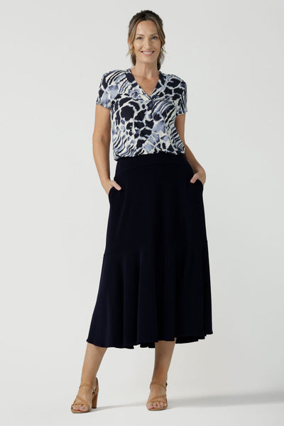 Woman wears a pull on, navy maxi skirt with ruffle hemline with a short sleeve flutter sleeve blue printed top. This black maxi skirt is a good workwear skirt or smart-casual skirt. Made in Australia in petite plus sizes 8-24.