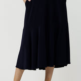 Front view of a woman wears a pull on, navy maxi skirt with ruffle hemline with a short sleeve flutter sleeve blue printed top. This black maxi skirt is a good workwear skirt or smart-casual skirt. Made in Australia in petite plus sizes 8-24.