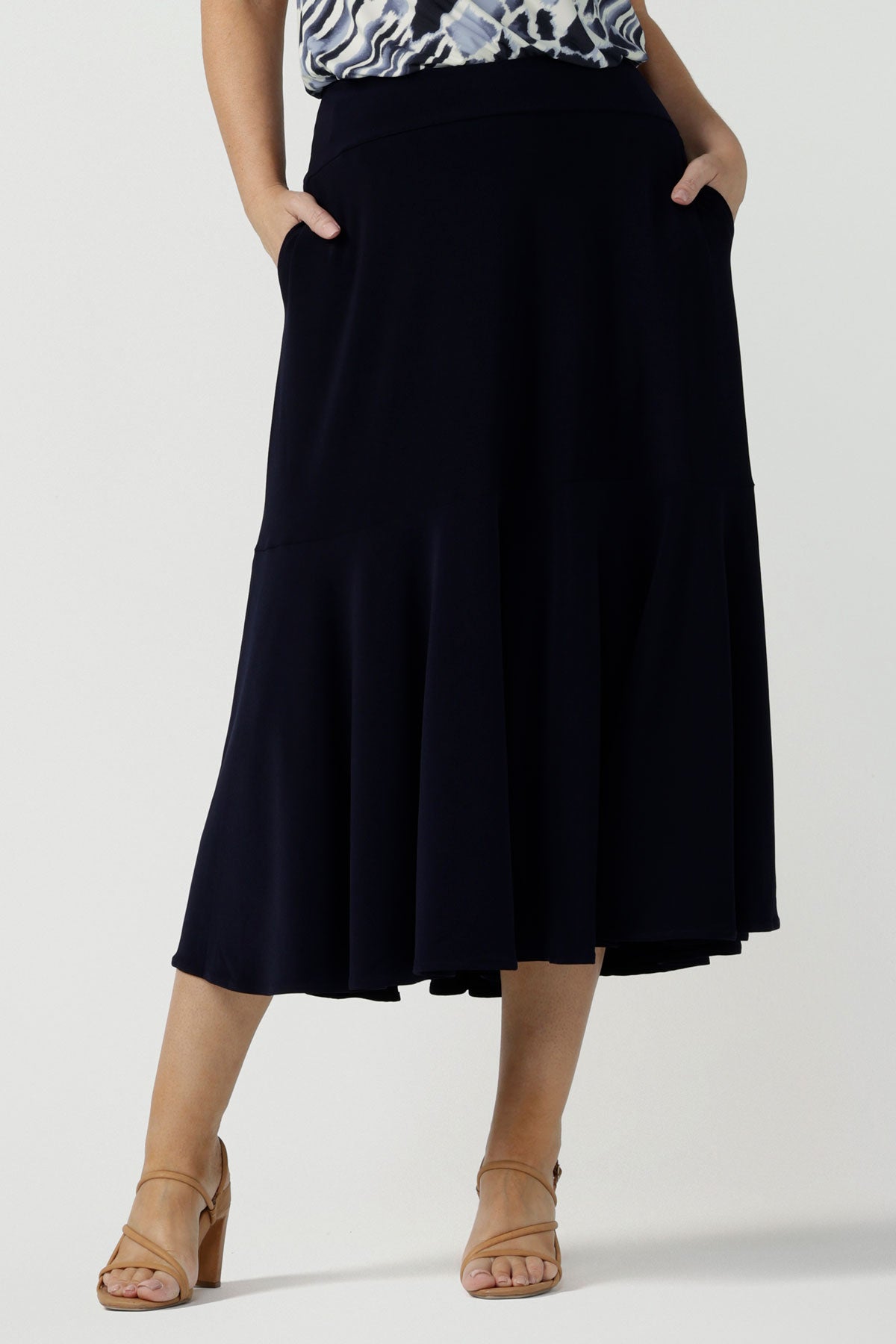 Front view of a woman wears a pull on, navy maxi skirt with ruffle hemline with a short sleeve flutter sleeve blue printed top. This black maxi skirt is a good workwear skirt or smart-casual skirt. Made in Australia in petite plus sizes 8-24.