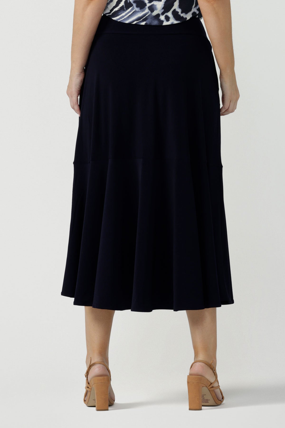 Back view of a woman wears a pull on, navy maxi skirt with ruffle hemline with a short sleeve flutter sleeve blue printed top. This black maxi skirt is a good workwear skirt or smart-casual skirt. Made in Australia in petite plus sizes 8-24.