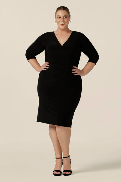 A great little black dress for evening and occasion wear, this is a fixed wrap, black jersey dress with 3/4 sleeves. Worn by a plus size, size 18 woman, shop this made-in-Australia dress in sizes 8 to 24.