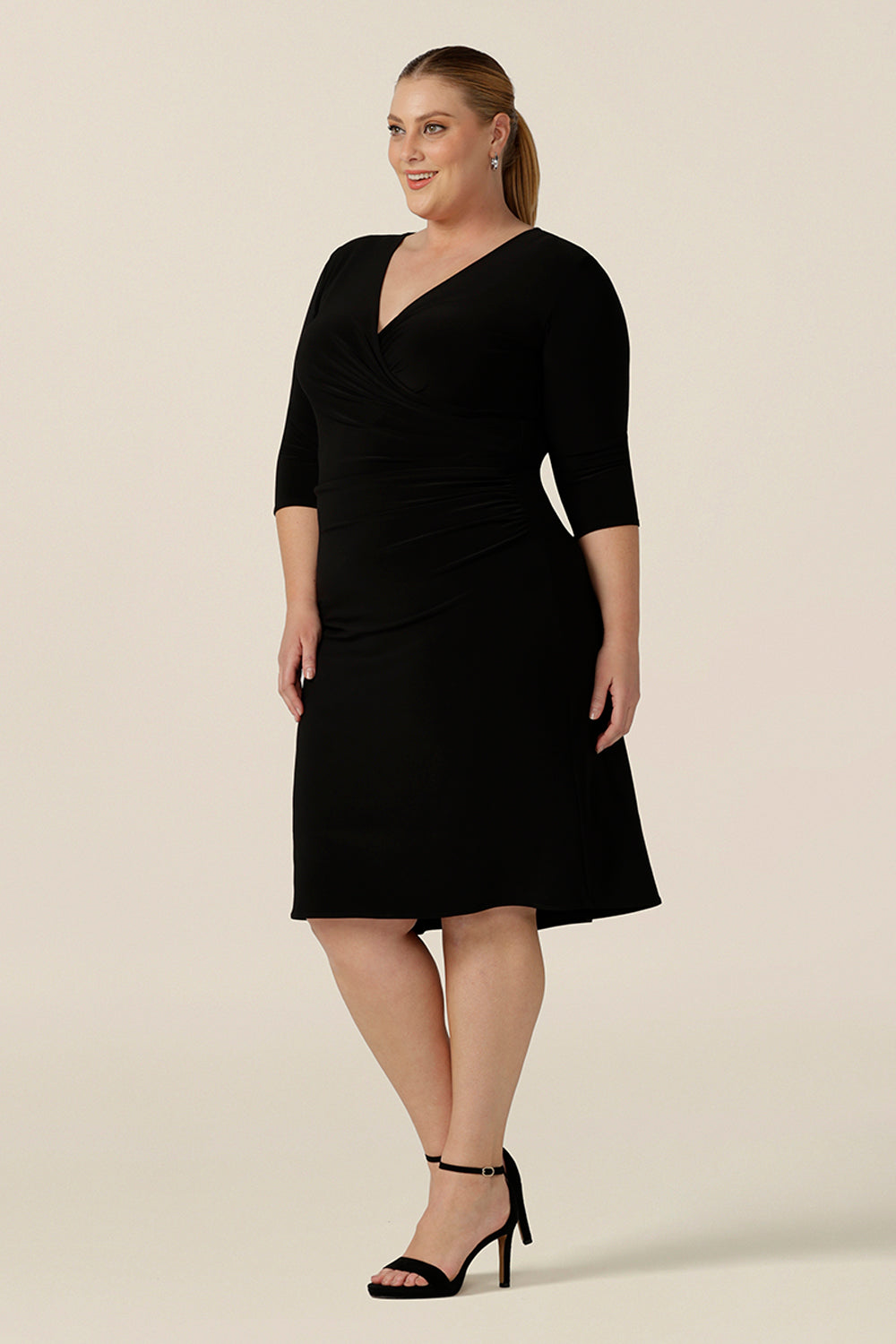 An elegant little black dress for evening and occasion wear, this is a fixed wrap, black jersey dress with 3/4 sleeves. Worn by a fuller figure, size 18 woman, shop this made-in-Australia dress in sizes 8 to 24.
