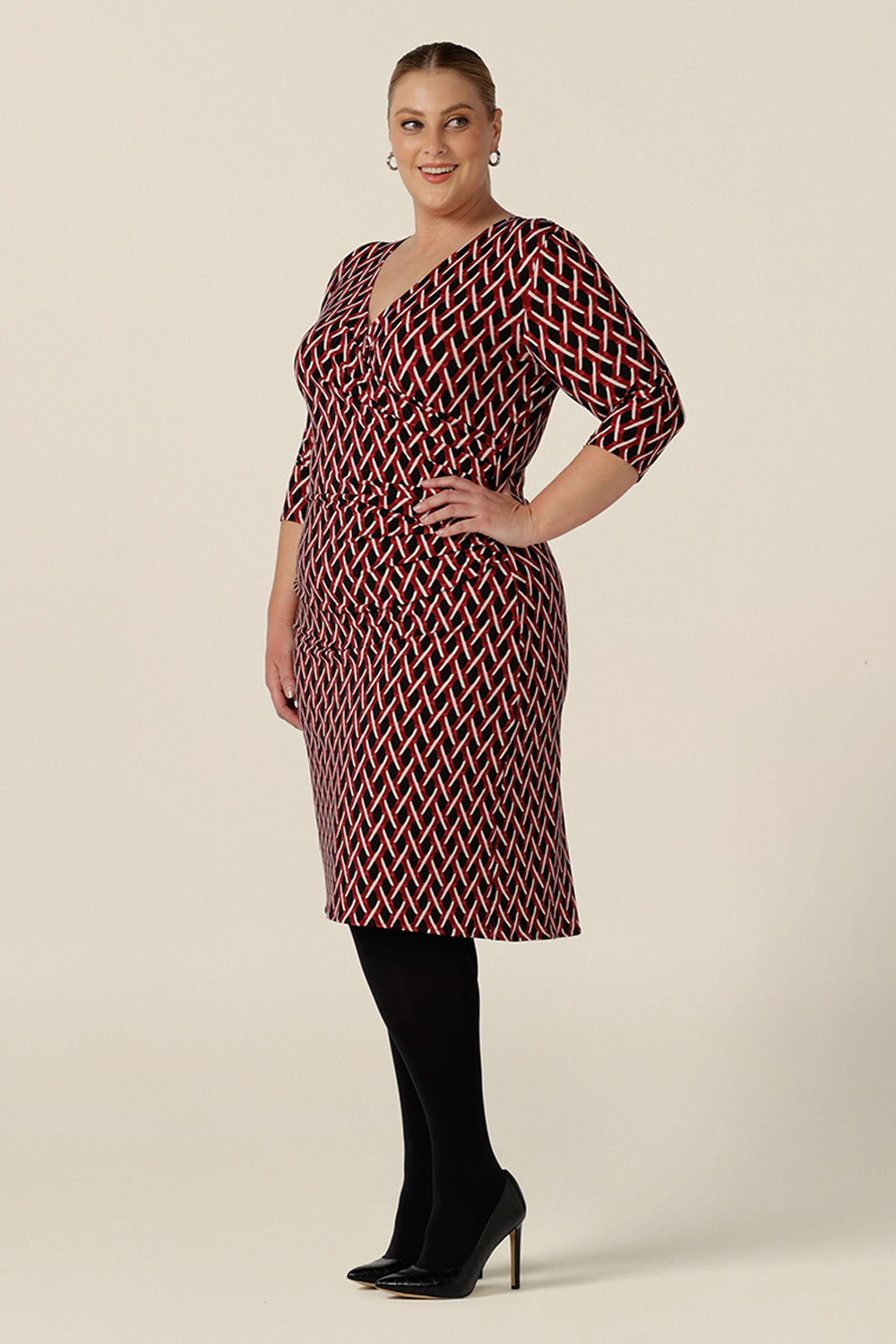 Side view of a plus size, size 18 woman wears a fitted wrap front dress with 3/4 sleeves by Australian fashion brand, Leina & Fleur. A good workwear dress, in printed jersey this is an easy-care dress for work wear capsule wardrobes.