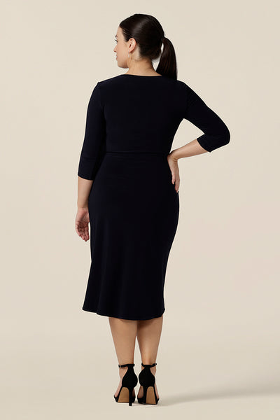 Back view of a classic navy blue dress for evening and occasion wear, this is a fixed wrap, navy jersey dress with 3/4 sleeves. Worn by a size 10 woman, this made-in-Australia dress is by Australian and New Zealand women's clothes label, Leina & Fleur and is available to shop in dress sizes 8 to 24.