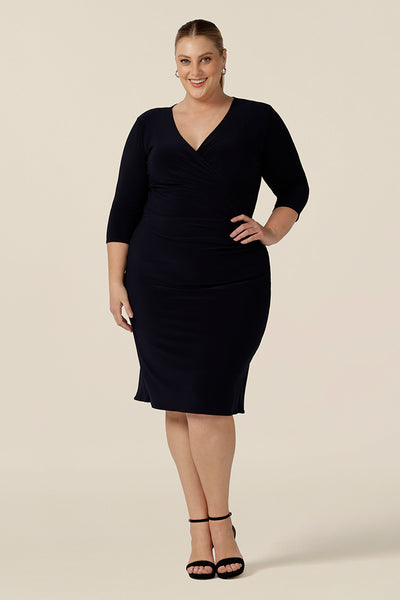 A classic navy blue dress for evening and occasion wear, this is a fixed wrap, navy jersey dress with 3/4 sleeves. Shown for plus sizes in size 18 , this made-in-Australia dress is by Australian and New Zealand women's clothes label, Leina & Fleur and is available to shop in dress sizes 8 to 24.