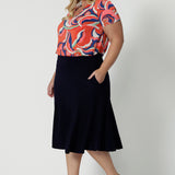 A good top for plus size women this tailored T-shirt top for summer, has a V-neck and short sleeves. Made in comfortable jersey, this printed top for women is worn by a size 18, curvy woman.  Worn with a knee length, navy skirt, this casual top  is good for travel and cruise wear. Made in Australia by Australian clothes label, Leina & Fleur in sizes 8 to 24.