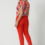 Made from tailored scuba crepe fabric in tangerine colour. Easy care pants are available in size 8-24. Australian made by clothing brand Leina & Fleur. Tapered leg pants are worn by size 18 model.