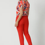 Made from tailored scuba crepe fabric in tangerine colour. Easy care pants are available in size 8-24. Australian made by clothing brand Leina & Fleur. Tapered leg pants are worn by size 18 model.