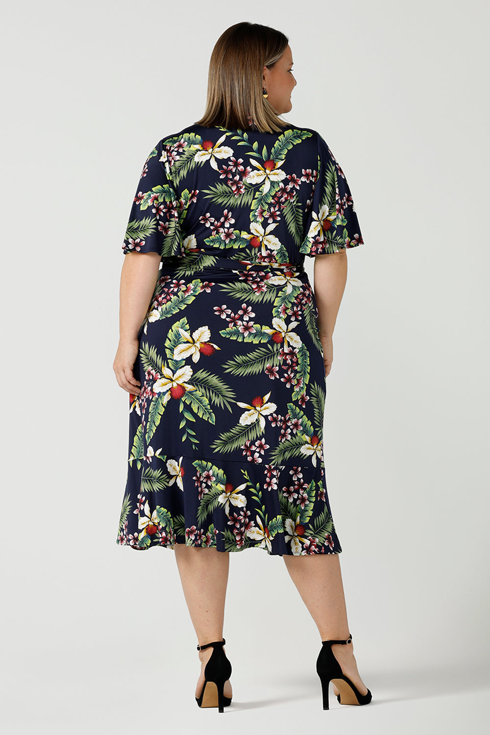 Back view of a plus size wrap dress for curvy women in festive Merriment print. Jersey wrap dress in soft jersey fabric with frilly hem and sleeves. Made in Australia size 8 - 24.
