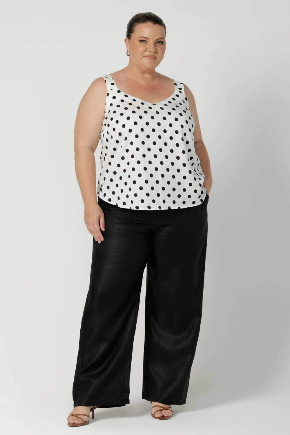 Proudly made in Australia, it is available in sizes 8-24, offering a flattering fit for a range of body types. Size 18 woman wears summer cami styled with black workwear pants and brown kitten heels, for an elevated look.