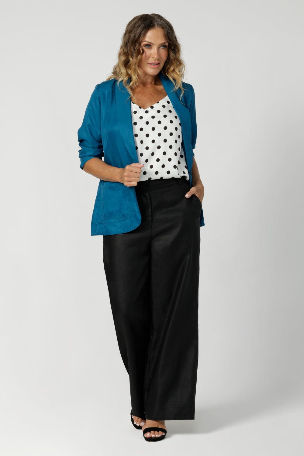 Image of model wearing black spotted white cami paired with black work wear pants, teal coloured blazer and heels, for an elevated workwear look. Australian made by clothing brand Leina & Fluer in inclusive sizing ranging from plus sized to petite in an 8-4.