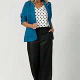 Image of model wearing black spotted white cami paired with black work wear pants, teal coloured blazer and heels, for an elevated workwear look. Australian made by clothing brand Leina & Fluer in inclusive sizing ranging from plus sized to petite in an 8-4.