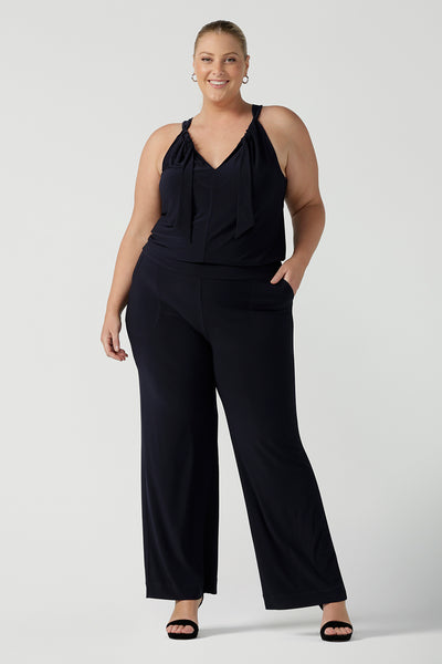 Plus size 18 women wears jumpsuit for curvy women. This navy jumpsuit features a halter neck with side pockets and straight legs. Made in Australia in navy stretch jersey this jumpsuit is comfortable for work or weekend wear.  