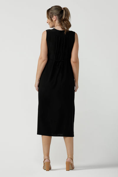 Back view of women's black dress in jersey for women. Pictured on a size 8 for petite to plus size women 8-24. Made in Australia in soft black jersey featuring a v-neckline and pleated front. 