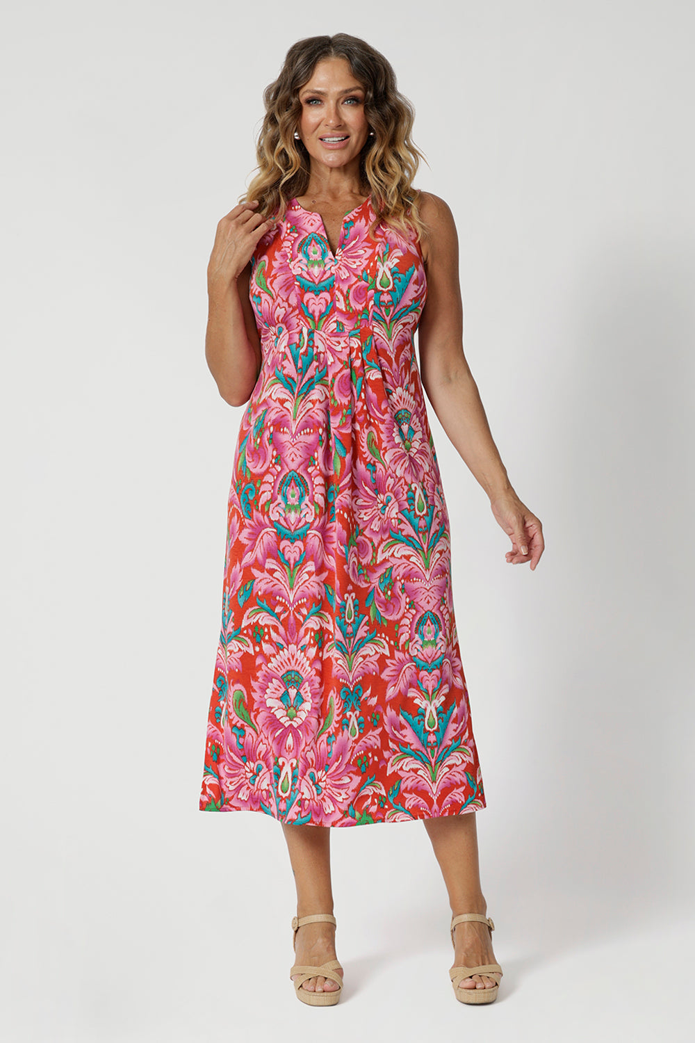 Over 40's woman wears v neck midi summer ready dress. The abstract tropical print of the dress embodies the essence of a resort lifestyle and beach getaways. Leina & Fleur have a collection of Indian Summer printed garments made of the same stretchy crepe jersey in sizes 8-24.