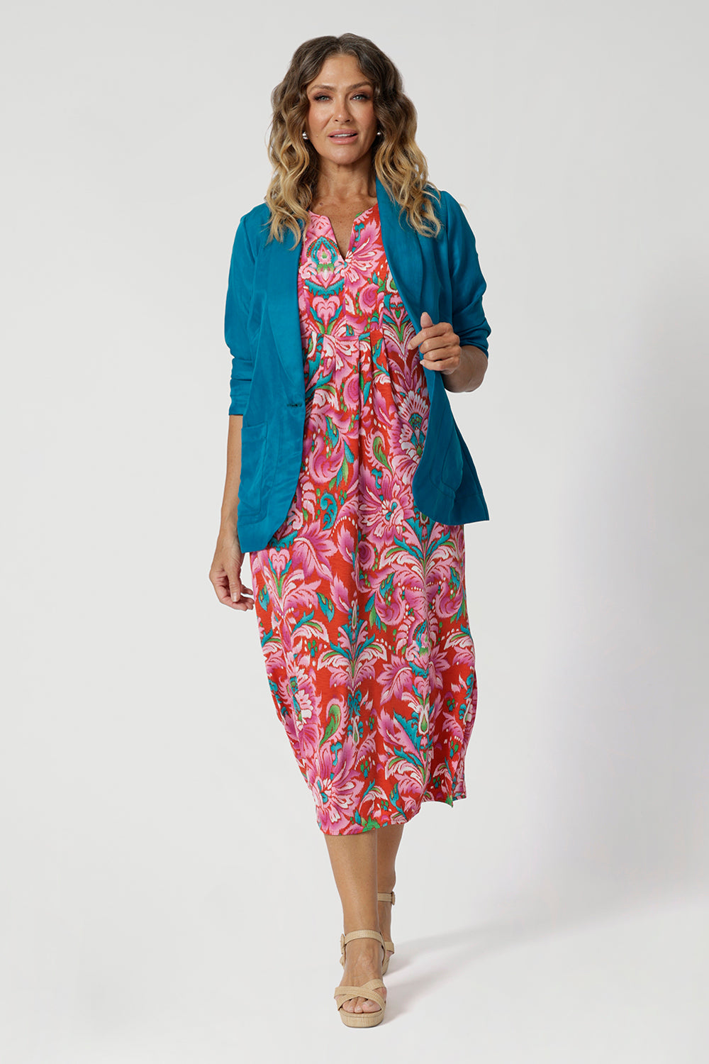 Size 12 model wears summer ready printed dress paired back with teal blazer to bring out the vibrant tropical print colours of red, orange, pink, blue, green and white. Fernanda Dress in Indian Summer stocked in sizes 8-24.