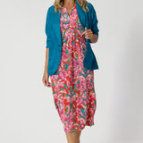 Size 12 model wears summer ready printed dress paired back with teal blazer to bring out the vibrant tropical print colours of red, orange, pink, blue, green and white. Fernanda Dress in Indian Summer stocked in sizes 8-24.