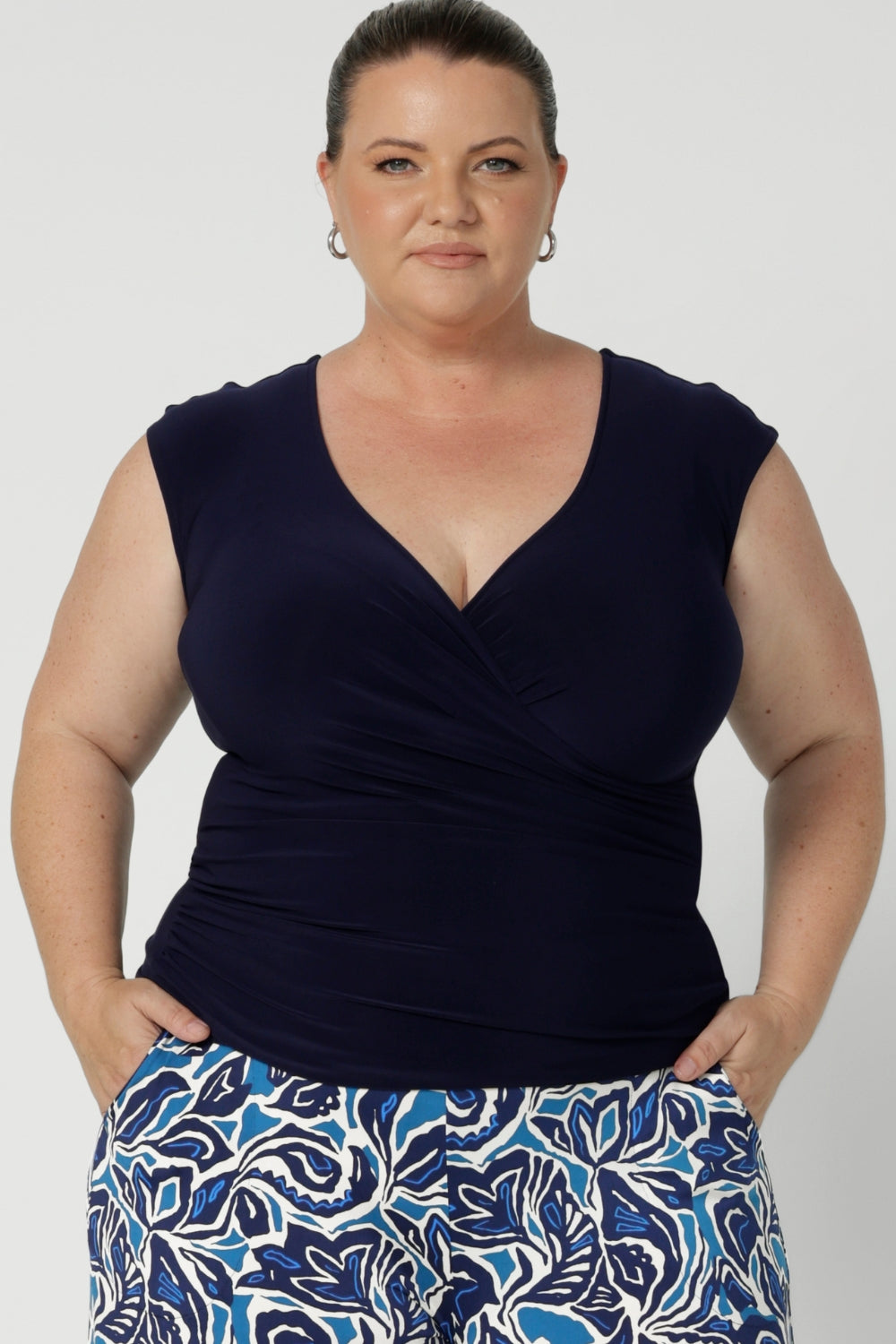 A size 18 curvy woman wears the Finely Top in Navy. A fixed wrap style perfect for corporate to casual wear. Made in Australia for women size 8 - 24.