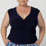 A size 18 curvy woman wears the Finely Top in Navy. A fixed wrap style perfect for corporate to casual wear. Made in Australia for women size 8 - 24.