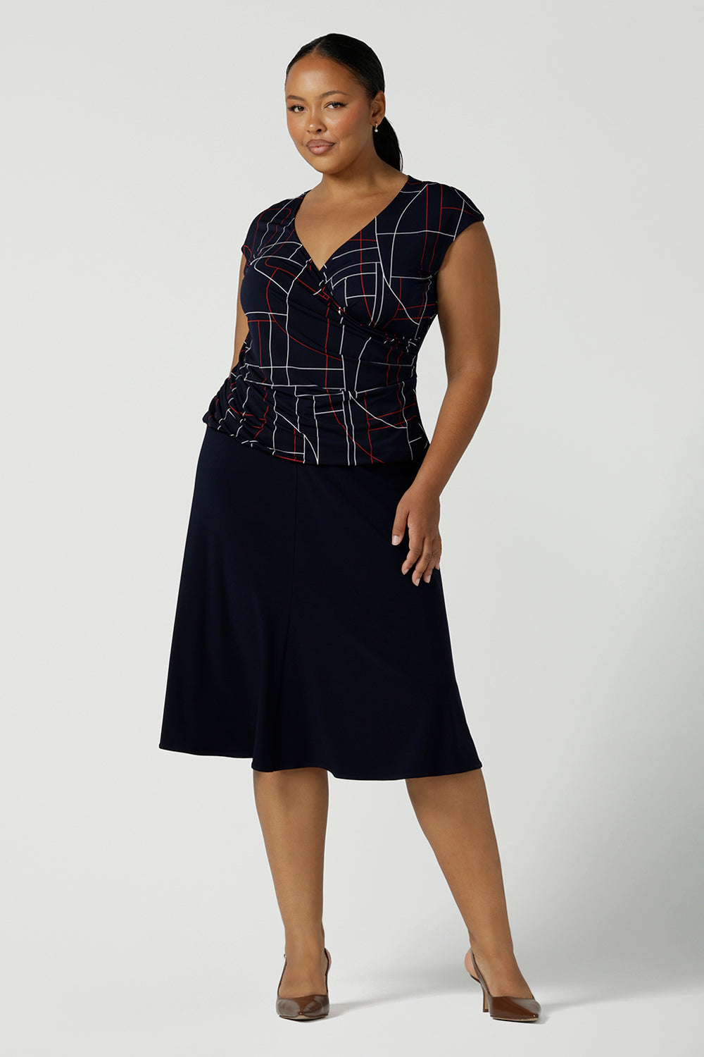 Size 16 woman wears a Finley Top in Navy abstract. Fixed wrap top with a geometric pattern. Styled back with a Navy skirt. Comfortable corporate wear for women. Made in Australia for women size 8 - 24. 