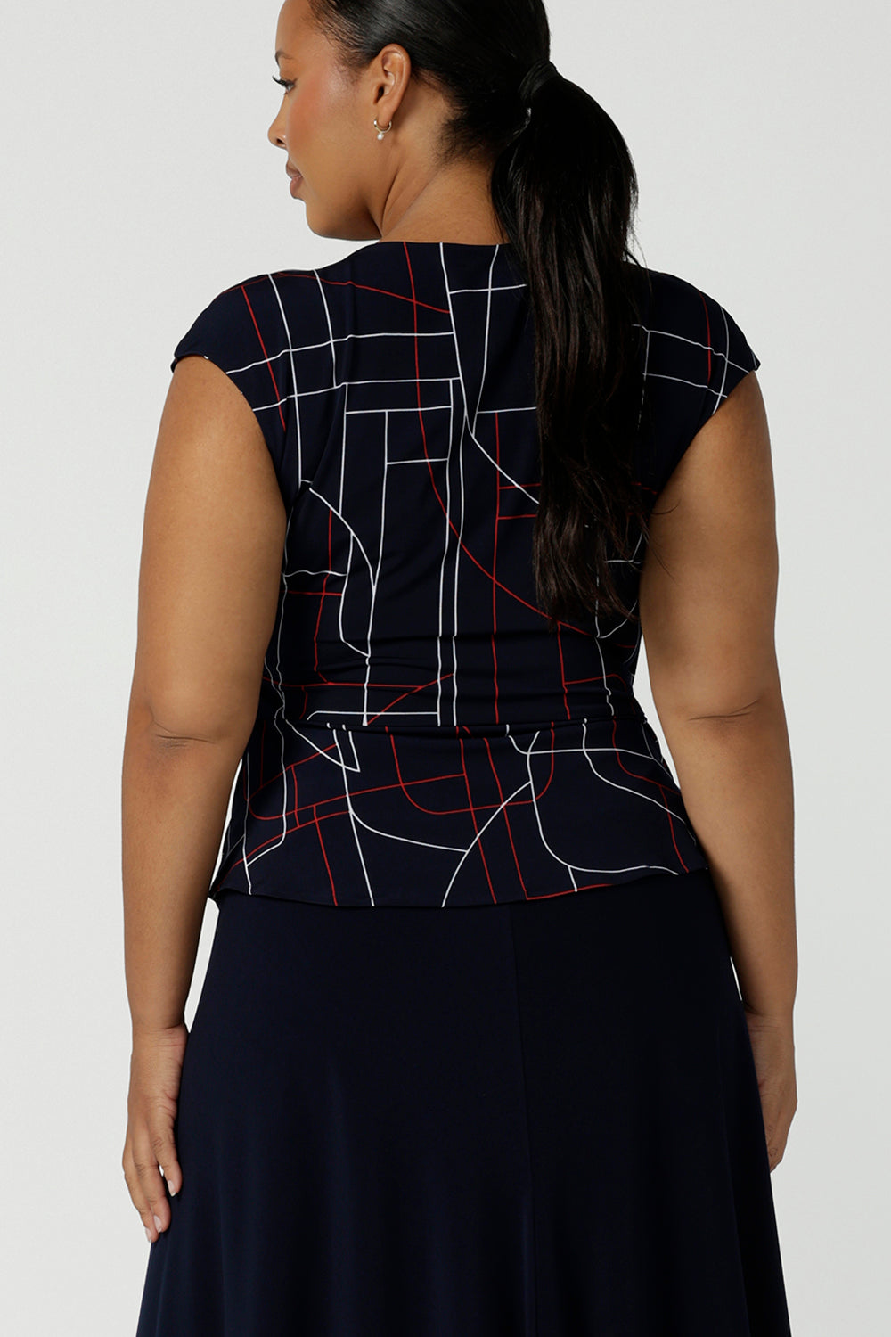 Back view of a size 16 woman wears a Finley Top in Navy abstract. Fixed wrap top with a geometric pattern. Styled back with a Navy skirt. Comfortable corporate wear for women. Made in Australia for women size 8 - 24.