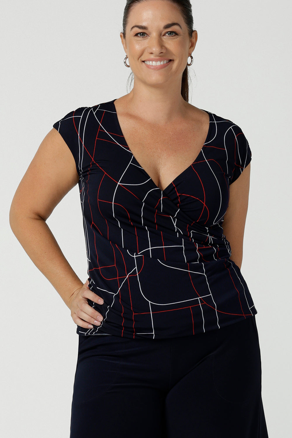 Size 12 woman wears a Finley Top in Navy abstract. Fixed wrap top with a geometric pattern. Styled back with a Navy skirt. Comfortable corporate wear for women. Made in Australia for women size 8 - 24.