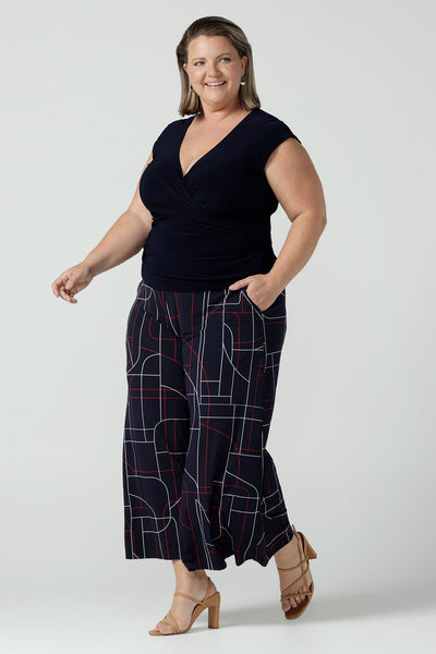 A size 16 curvy woman wears the Finely top in Navy. A fixed wrap style perfect for corporate to casual wear. Made in Australia for women size 8 - 24.