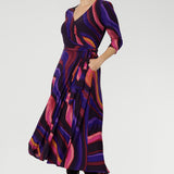 The Fiona Wrap Dress in Jupiter is a vibrant and sophisticated wardrobe essential, showcasing a colourful swirly print that brings energy and movement to every step. 