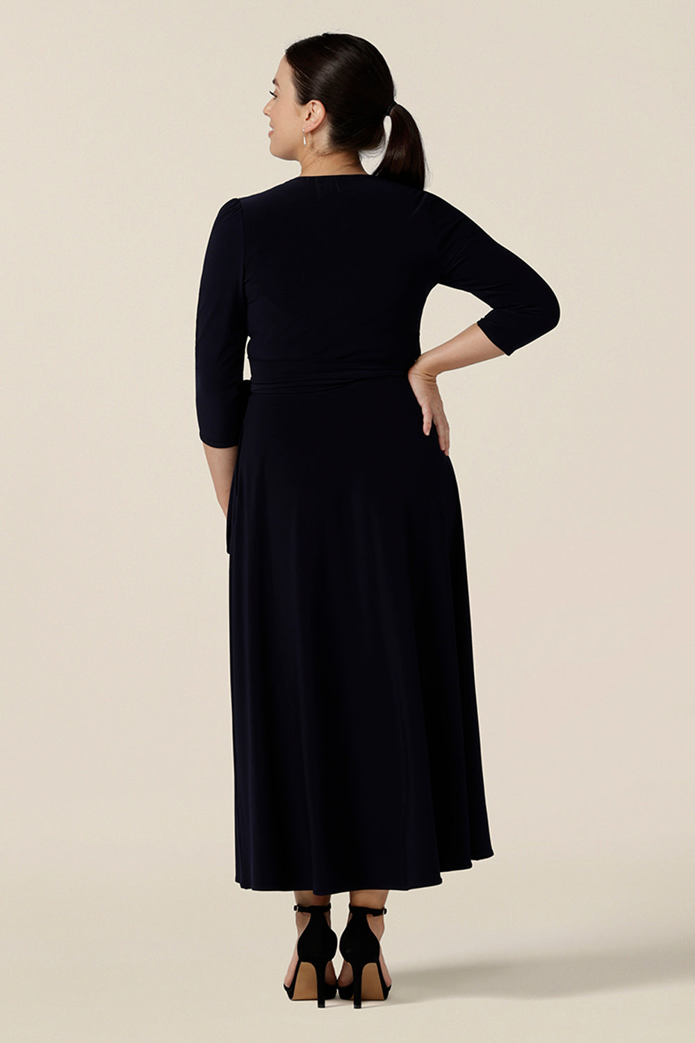 Shown for petite height women, this is the back view of a navy blue wrap dress with 3/4 sleeves. With a full, midi skirt, this jersey dress is a good dress for evening and occasion wear. Made in Australia, shop dresses in sizes 8 to 24.