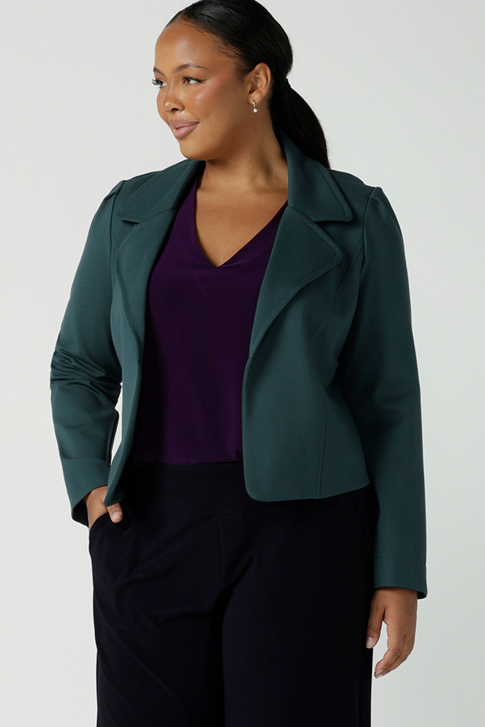 Size 10 woman wears the Garcia Jacket in Alpine styled back with the Vida Top in Amethyst. A v-neckline style with 3/4 sleeves. Styled back with Monroe in Navy. A comfortable corporate work pant. Size 8 - 24.