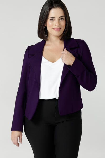A size 10 woman wears the Garcia jacket in Alpine, a amethyst purple jacket with tailored details in a soft stretch ponte jersey. Comfortable and stylish workwear for women. Styled back with black brooklyn best selling pants. Made in Australia for women size 8 - 24,