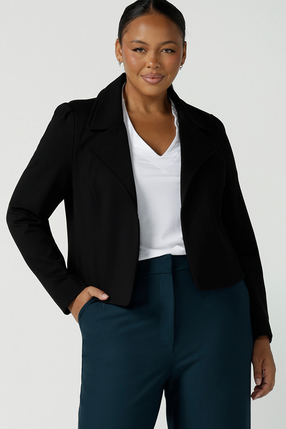 Size 16 woman wears the Garcia Jacket in Black. Tailored design with collar and comfortable stretch. Comfortable and stylish workwear for women. Size inclusive fashion and made in Australia for women size 8 - 24. Styled back with Yael wide leg pants in Petrol. 