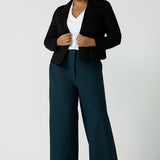 Size 16 woman wears the Garcia Jacket in Black. Tailored design with collar and comfortable stretch. Comfortable and stylish workwear for women. Size inclusive fashion and made in Australia for women size 8 - 24. Styled back with Yael wide leg pants in Petrol.