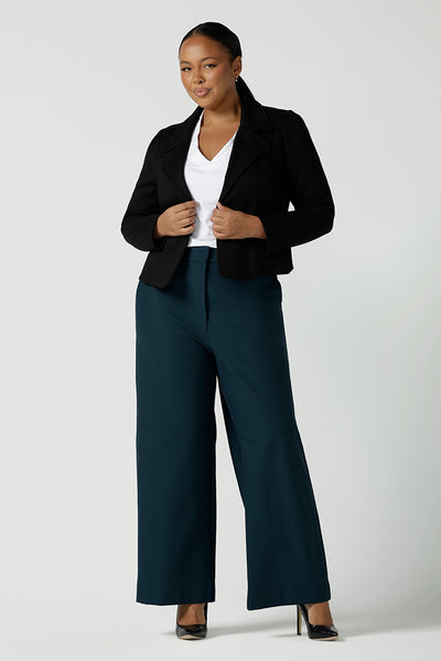 Size 16 woman wears the Garcia Jacket in Black. Tailored design with collar and comfortable stretch. Comfortable and stylish workwear for women. Size inclusive fashion and made in Australia for women size 8 - 24. Styled back with Yael wide leg pants in Petrol.