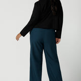 Back view of a size 16 woman wears the Garcia Jacket in Black. Tailored design with collar and comfortable stretch. Comfortable and stylish workwear for women. Size inclusive fashion and made in Australia for women size 8 - 24. Styled back with Yael wide leg pants in Petrol.