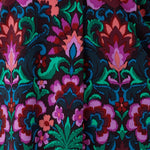 This vibrant printed fabric, featuring bold hues of pink, green, burgundy, and blue, is used to create a stunning collection of women’s spring fashion, including a maxi wrap dress, culotte pants, and a flutter sleeve top. Proudly made in Australia and available in sizes 8 to 24.