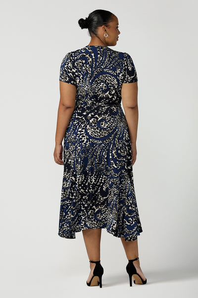 Back view of a size 18 plus size woman wearing a animal print jersey wrap dress with tailored godets in the skirt. A good wrap dress for summer, shop Australian-made plus size wrap dresses online at Australian fashion brand Leina & Fleur.