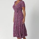 Over 40's woman wears wrap-style dress silhouette, that hugs the body in all the right places while offering a comfortable fit for a wide range of shapes and sizes, from 8 to 24, including petite and plus sizes. Crafted from easy care fabric by Leina & Fleur. 