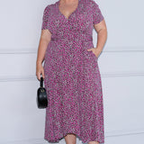 Midi length dress seen on plus size model is made from easy care, luxurious jersey fabric. Size 18 model wears printed dress paired with black heels and a black purse, creating an elevated summer styling look.