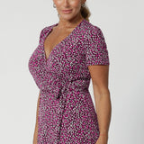 Over 40's woman wears wrap-style dress silhouette, that hugs the body in all the right places while offering a comfortable fit for a wide range of shapes and sizes, from 8 to 24, including petite and plus sizes. Crafted from easy care fabric by Leina & Fleur. 