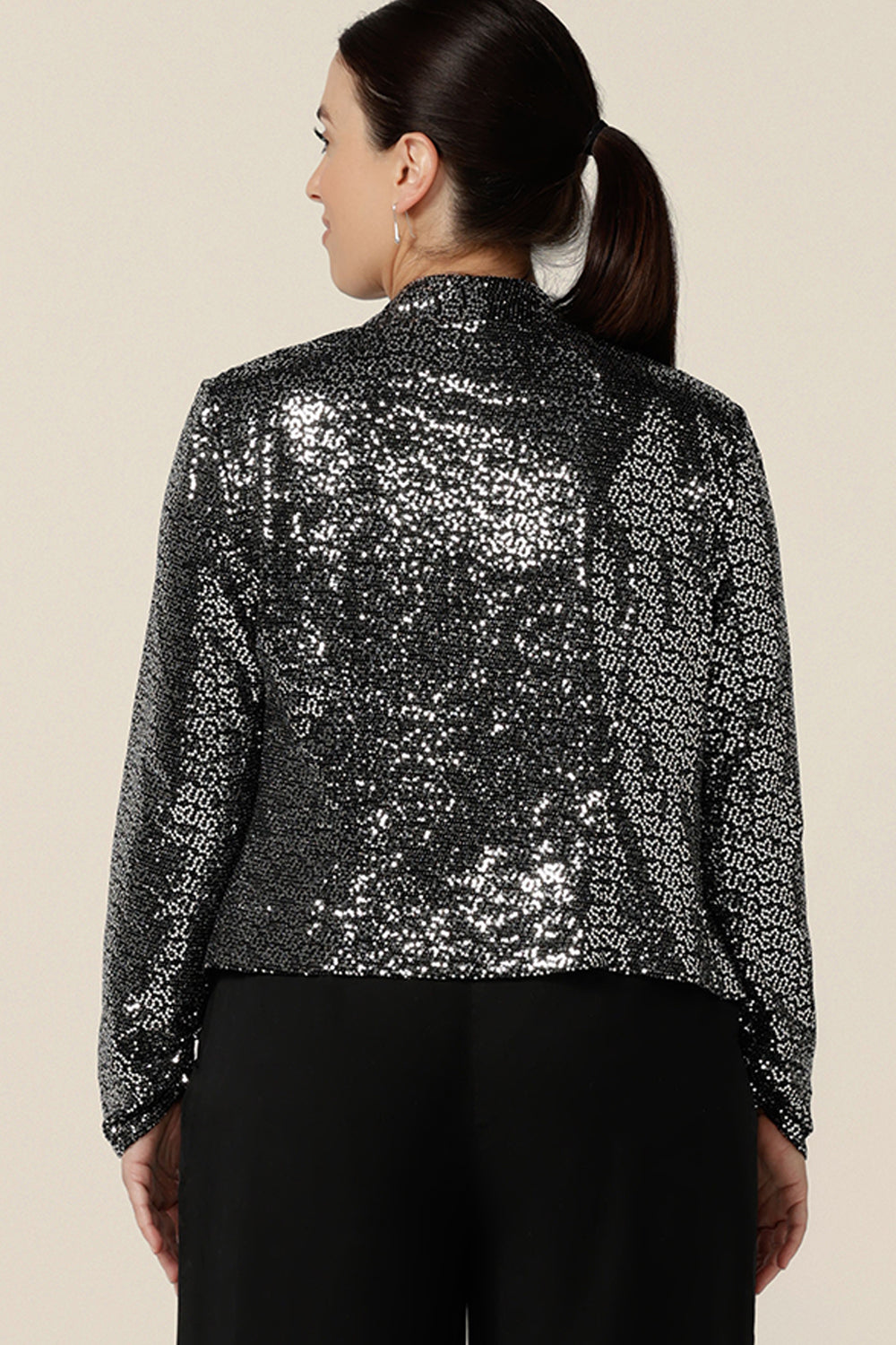 BAck view of a size 10, petite height woman wearing a silver sequin jacket with waterfall front for evening and event wear. Styled with a plum cami top, this sparkly jacket is glamorous cocktail attire at it's finest! Made in Australia by women's occasionwear brand, Leina & Fleur, shop cocktail jackets online in petite to plus sizes.
