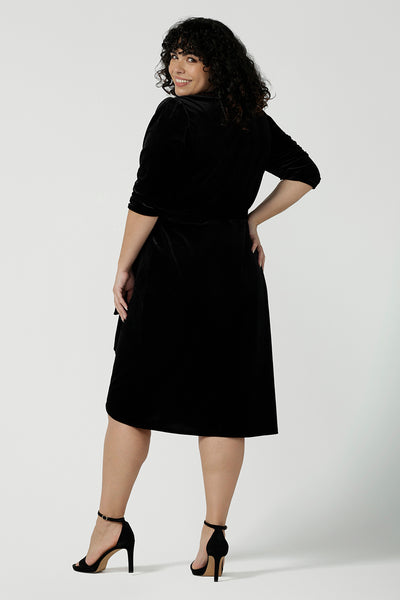 Back view of a curvy size 18 model wears the Hedy dress in Black. A velour functioning wrap dress with a tulip skirt and draped front. Up Late evening wear for event dressing. Size inclusive sustainable fashion made in Australia size 8 - 24.