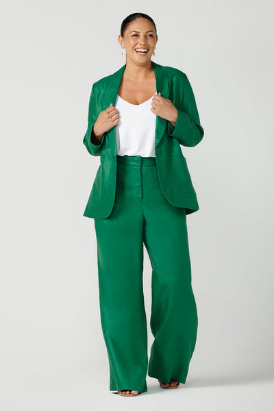 A size 12 happy woman wears a soft linen blazer jacket with a tailored design. A transeasonal linen work jacket, in a beautiful emerald green colour. Australian-made using sustainable 100% linen fabric. Size-inclusive fashion 8-24 for corporate casual workwear.