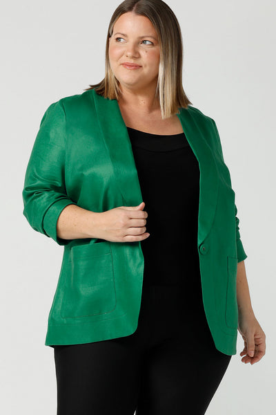 A size 18 woman wears a 100% linen blazer jacket with a tailored design. Breathable linen fabric. This blazer has a relaxed fit a button front construction. A transeasonal linen work jacket, in a beautiful emerald green colour. Australian-made using sustainable 100% linen fabric. Size-inclusive fashion 8-24 for corporate casual workwear.